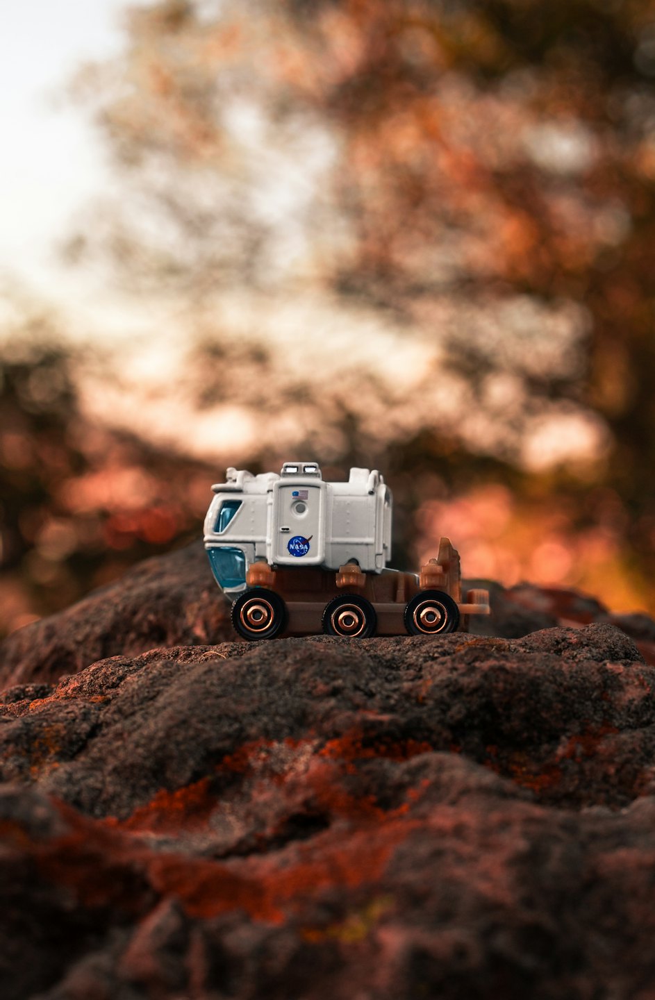 Small NASA rover on a reddish-brown rock surface.