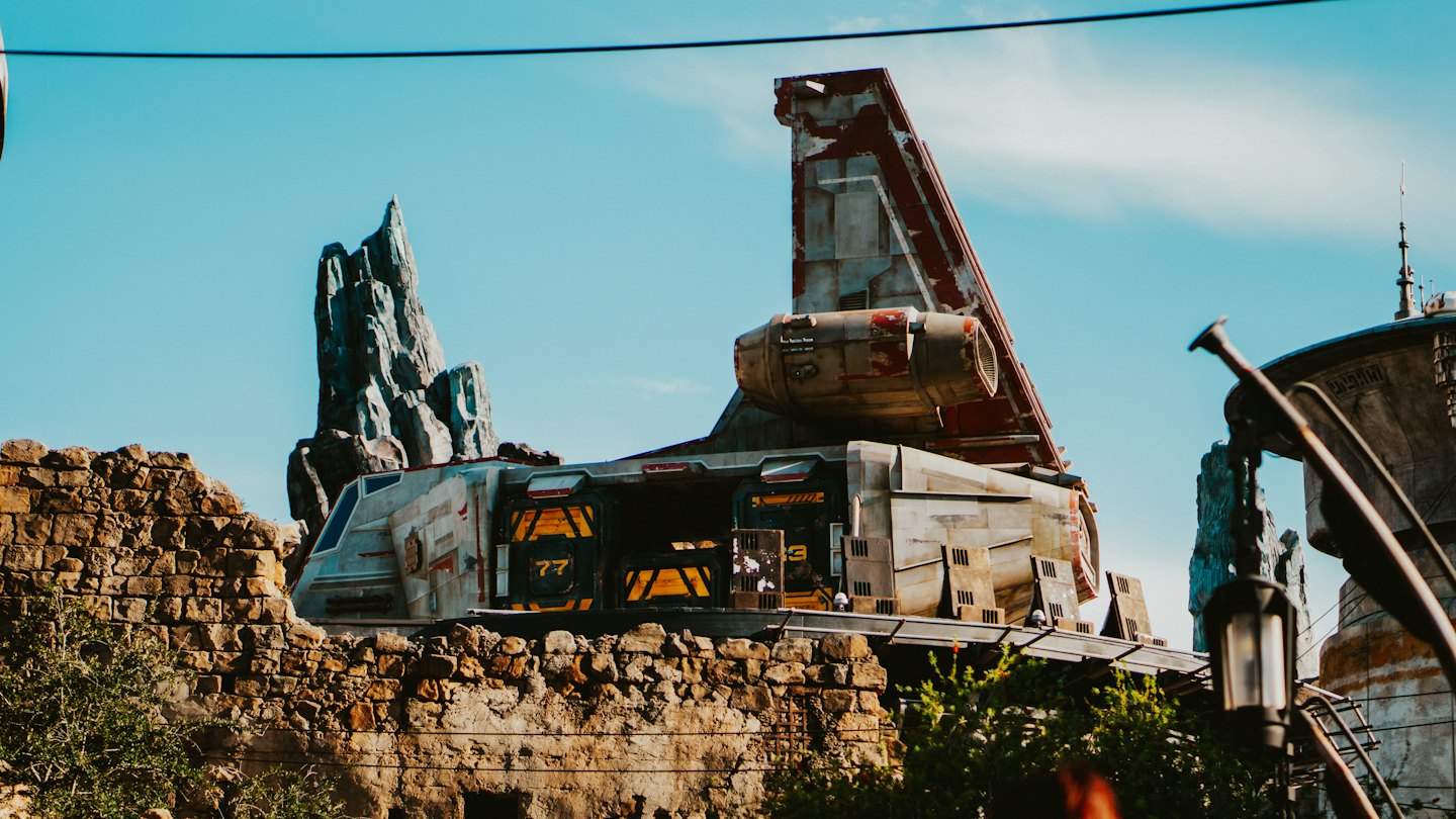 A weathered futuristic spacecraft parked among crumbling stone walls.