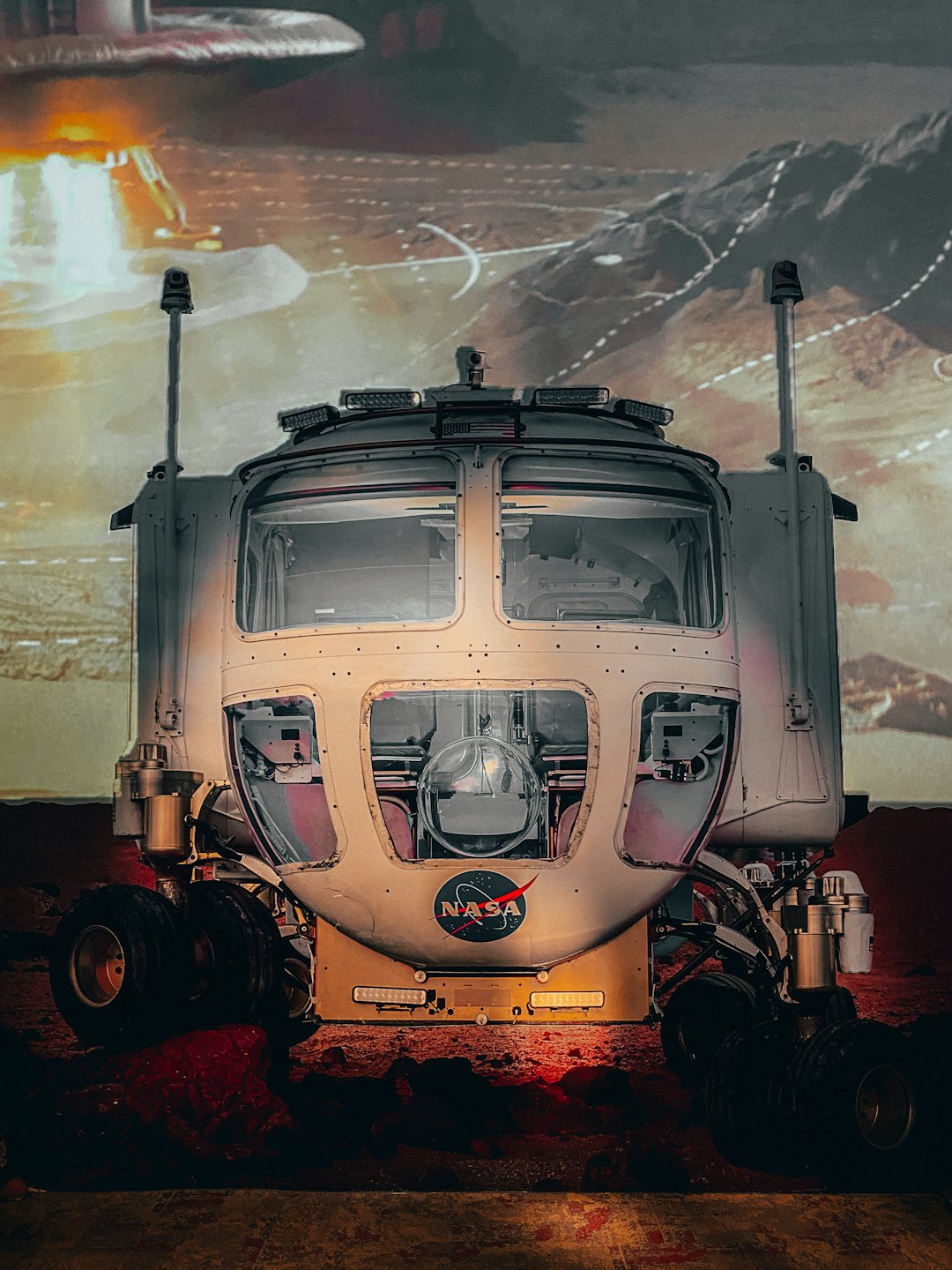 A white NASA Mars rover prototype stands on red terrain.